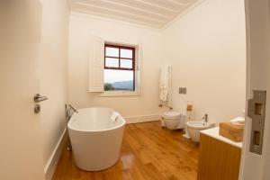 a white bathroom with a tub and two toilets at Quinta da Corredoura, Hotel Rural in Guimarães