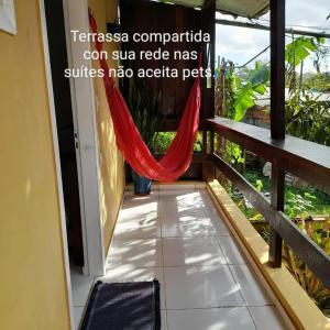 a room with a hammock on a balcony at SUITES E CHALES PRIVADOS Rock's&Rose's home in Camburi