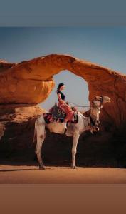 a person riding a camel in the desert at Tamim Luxury wadi rum camp in Wadi Rum