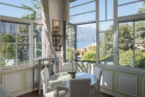 a dining room with large windows and a table and chairs at Bellagio Vintage Apartment in Bellagio