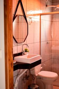 a bathroom with a sink and a toilet and a mirror at Pousada do Nondas in Nobres