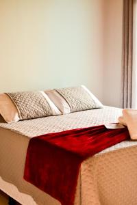 Una cama con una manta roja encima. en Pousada do Nondas, en Nobres