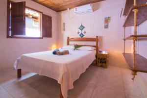1 dormitorio con 1 cama con manta blanca en Pousada Azul com vistas maravilhosas, en Cumuruxatiba