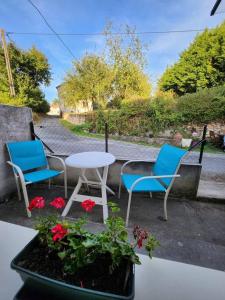 a patio with two chairs and a table and flowers at La maison du sabotier in Oradour-Saint-Genest