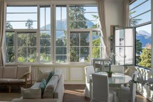 un soggiorno con finestre, tavolo e sedie di Bellagio Vintage Apartment a Bellagio