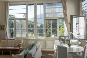 a living room with large windows and a table at Bellagio Vintage Apartment in Bellagio