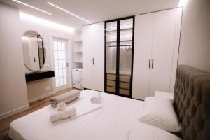 ein weißes Zimmer mit einem Bett und einem Spiegel in der Unterkunft Aljas Luxury Apartment in Tirana