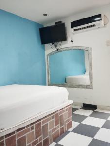 1 dormitorio con cama, espejo y suelo a cuadros en Príncipe azul, en Puerto Colombia