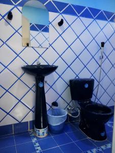 a bathroom with a black toilet and a sink at Príncipe azul in Puerto Colombia