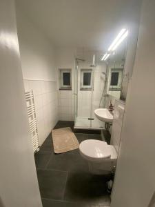 a bathroom with two sinks and a toilet and a mirror at Messewohnung/Monteurwohnung in Garbsen