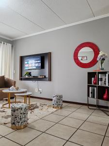 een woonkamer met een bank en een tv aan de muur bij Tevin Nest in Sandton