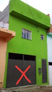 a green building with a gate with a x on it at Kit net montanha mágica in São Thomé das Letras