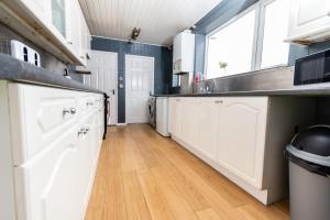 uma cozinha com armários brancos e piso em madeira em Malvern - Beautiful 2 bed upper flat Ideal for Contractors Free Parking em South Shields