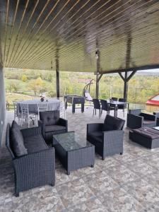 a patio with couches and tables and a roof at Casa dintre munti in Novaci-Străini