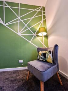 a chair with a lamp next to a green wall at Modern 2 bedroom flat County Rd in Liverpool