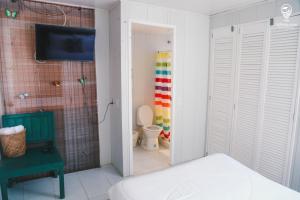 a bedroom with a bathroom with a toilet and a tv at Blue Sand House B&B in Cartagena de Indias