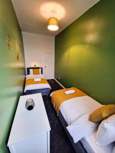 a room with two beds and a green wall at Modern 2 bedroom flat County Rd in Liverpool