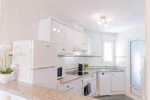 eine weiße Küche mit weißen Geräten und weißen Schränken in der Unterkunft Zafiro Apartment Cabo Roig in Orihuela + 12 Fotos