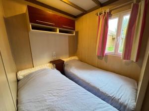 two beds in a small room with a window at Les maisonnettes du lac - base de loisirs Lavaré in Lavaré