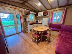 - un salon avec une table et un canapé violet dans l'établissement Les maisonnettes du lac - base de loisirs Lavaré, à Lavaré