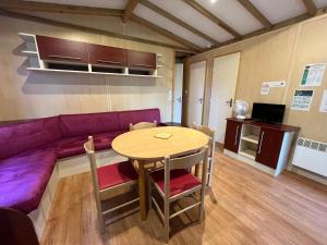 a living room with a purple couch and a table at Les maisonnettes du lac - base de loisirs Lavaré in Lavaré