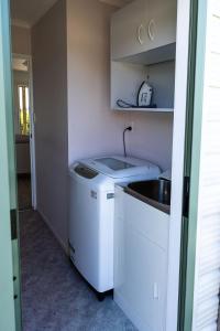 una pequeña cocina con fregadero y lavavajillas en Fantail Cottage, en Hamilton