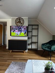 a living room with a television and a clock on the wall at Suite 3 SZ - Lichtenberg in Salzgitter