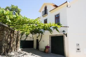 Milheirós de Poiares的住宿－卡薩蘇亞雷斯農家樂，一座白色的房子,有黑色的大门和一座建筑