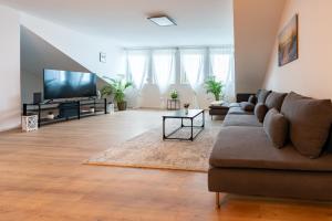 ein Wohnzimmer mit einem Sofa und einem Flachbild-TV in der Unterkunft Apartment im Dachgeschoss in Plankstadt