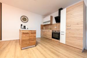 Apartment im Dachgeschoss في Plankstadt: مطبخ مع دواليب خشبية وساعة على الحائط