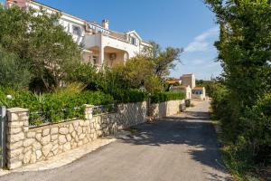 a road in front of a house with a stone wall at Apartments Villa Tereza in Novalja