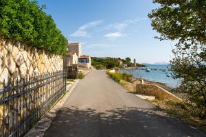 an empty road next to a wall and water at Apartments Villa Tereza in Novalja