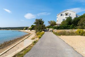 a path next to a beach with a white house at Apartments Villa Tereza in Novalja