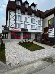 um edifício de hotel com um pátio de pedra em frente em Apartments Myna in Kraljevi Cardaci em Kopaonik