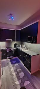 a kitchen with black and purple cabinets and a sink at Moderni kaksio Kuopion keskustassa in Kuopio