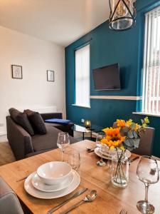 a dining room with a table with plates and wine glasses at Modern 2 bedroom flat County Rd in Liverpool