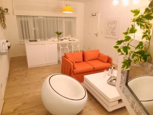 un soggiorno con sedia arancione e divano di The Luxury White Suite a Charleroi