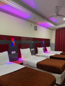 um quarto com três camas com luzes roxas em Saeed Hotel em Dubai