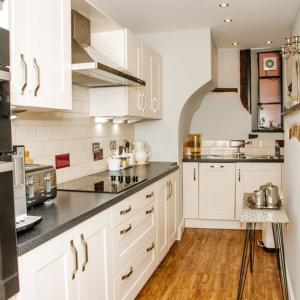 una cocina con armarios blancos y encimeras negras en Whispering Place in the heart of Bewdley, en Bewdley
