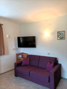 a living room with a purple couch and a flat screen tv at Haus Reiterer in Neustift im Stubaital