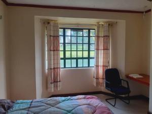 Schlafzimmer mit einem Bett und einem Fenster mit einem Stuhl in der Unterkunft Accommodation in Vihiga Bnb in Koiparak