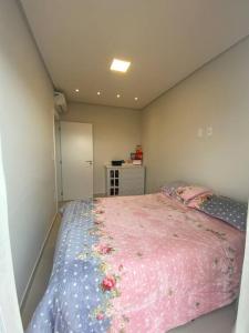 una camera da letto con un letto rosa con fiori di Atalaia 304 a Navegantes