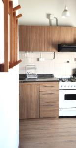 a kitchen with wooden cabinets and white appliances at Las Hortensias - Depto en Bariloche in San Carlos de Bariloche