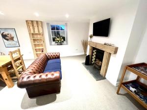 a living room with a leather couch and a fireplace at No. 20 The Headland in Hartlepool