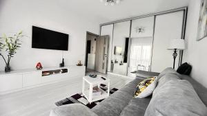 uma sala de estar com um sofá e uma televisão de ecrã plano em ONE Apartment Militari em Bucareste
