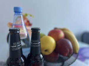 duas garrafas de cerveja sentadas ao lado de uma taça de fruta em ONE Apartment Militari em Bucareste