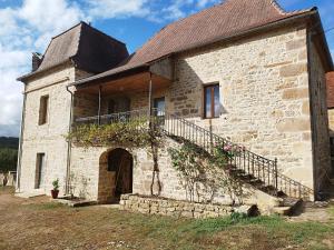 um antigo edifício de tijolos com uma varanda e flores em Mas des maries em Lissac et Mouret