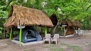 ein kleines Zelt mit Stühlen und einem Strohdach in der Unterkunft Eco-Camping El Frutal in Isla Grande