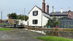 a white house sitting next to a body of water at The Stables, Chester - Luxury Apartments by PolkaStays in Chester