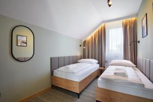 two beds in a room with a mirror at Boska Gąska Domki Wypoczynkowe in Gąski